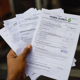 Gümrük belge kontrolü yapan bir elin yakın çekimi, arka planda Marin Global şirketinin logosu, 280x280 piksel, yüksek detaylı, gerçekçi, profesyonel